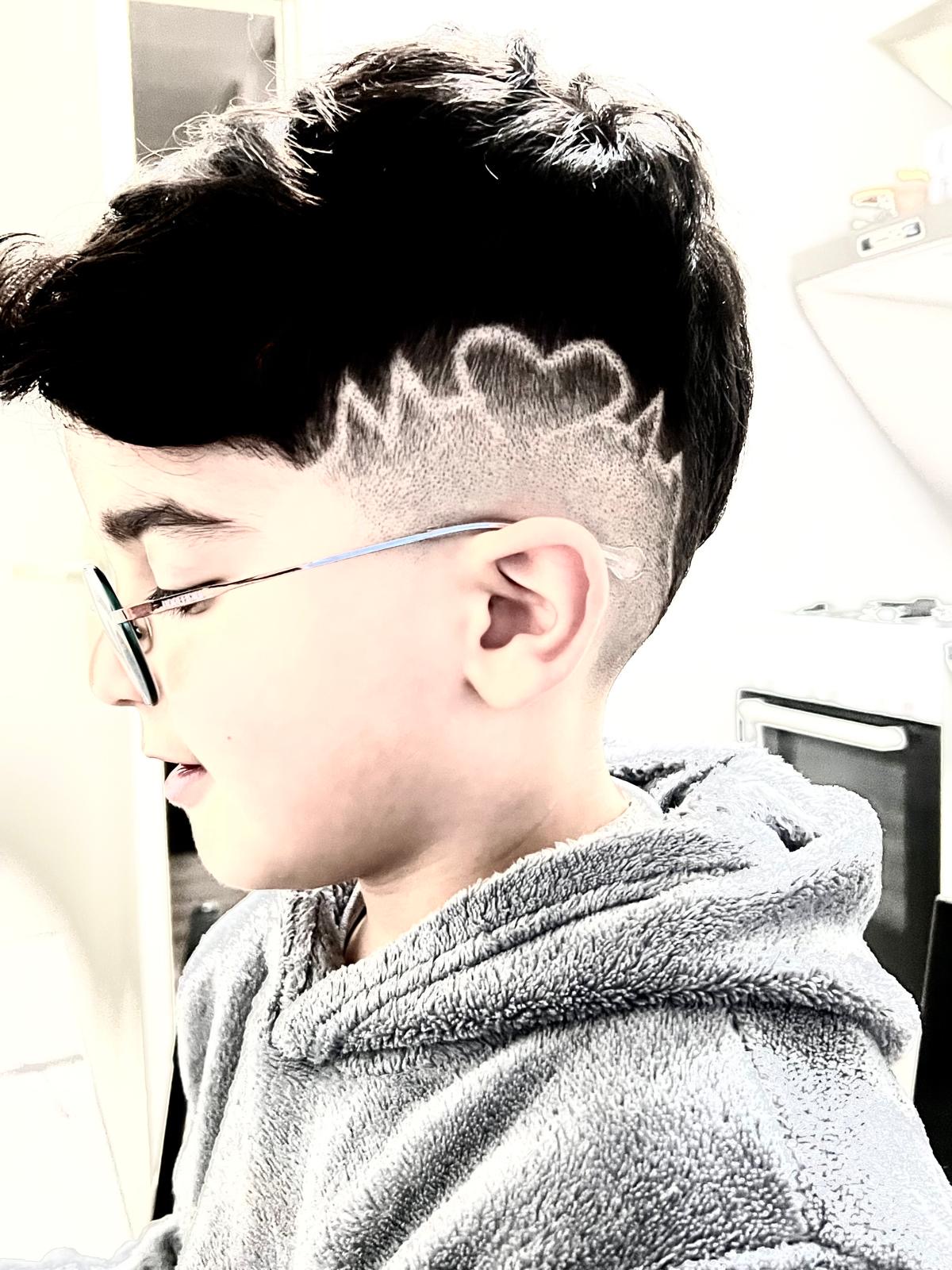 Een jongen met bril en een patroon in de zijkant geschoren